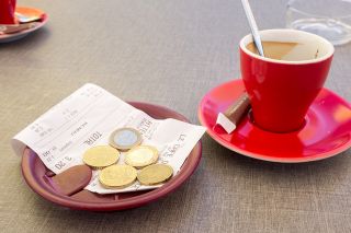 © Image'in - stock.adobe.com Foto: Kaffeetasse mit Rechnung und Münzen